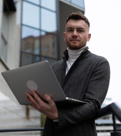 portrait of a young businessman with a laptop outside the office.